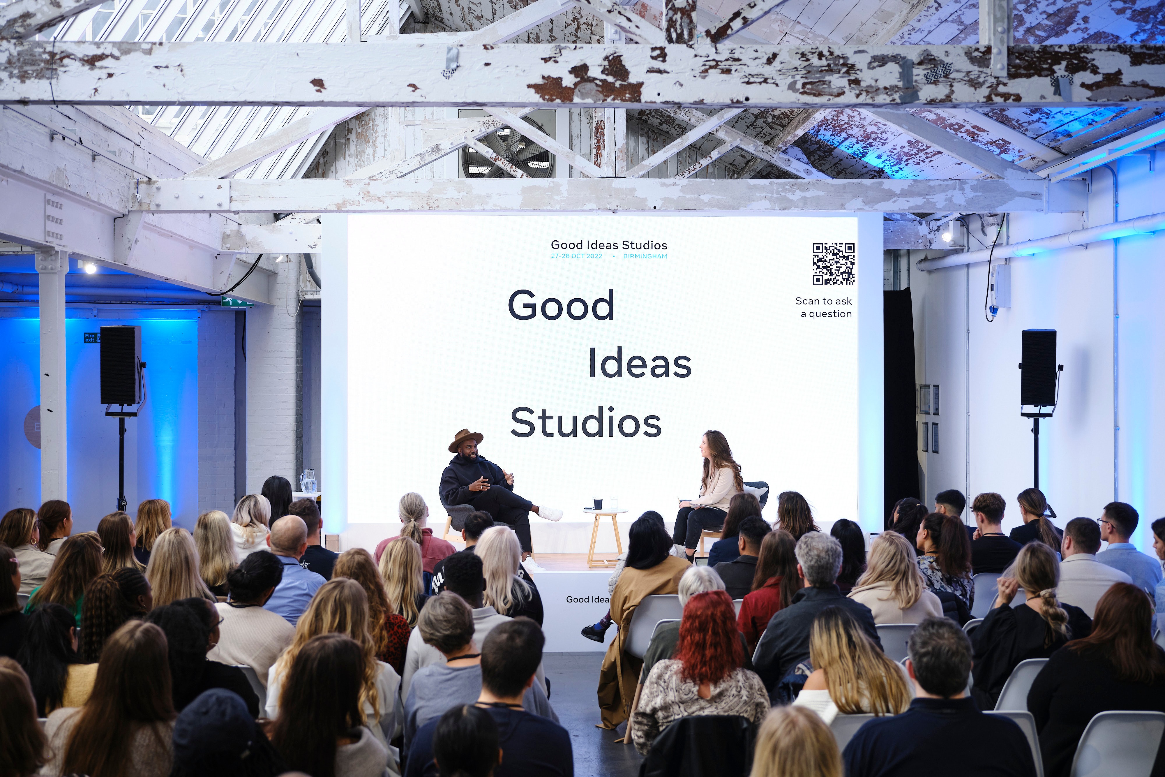 Room of people watching two people talk on stage